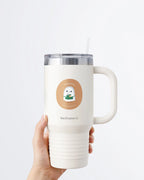Hand holding a tumbler displaying Nuts & Lemons Co. diecut sticker featuring  a cute ghostie barista making a latte with the phrase “boorista”