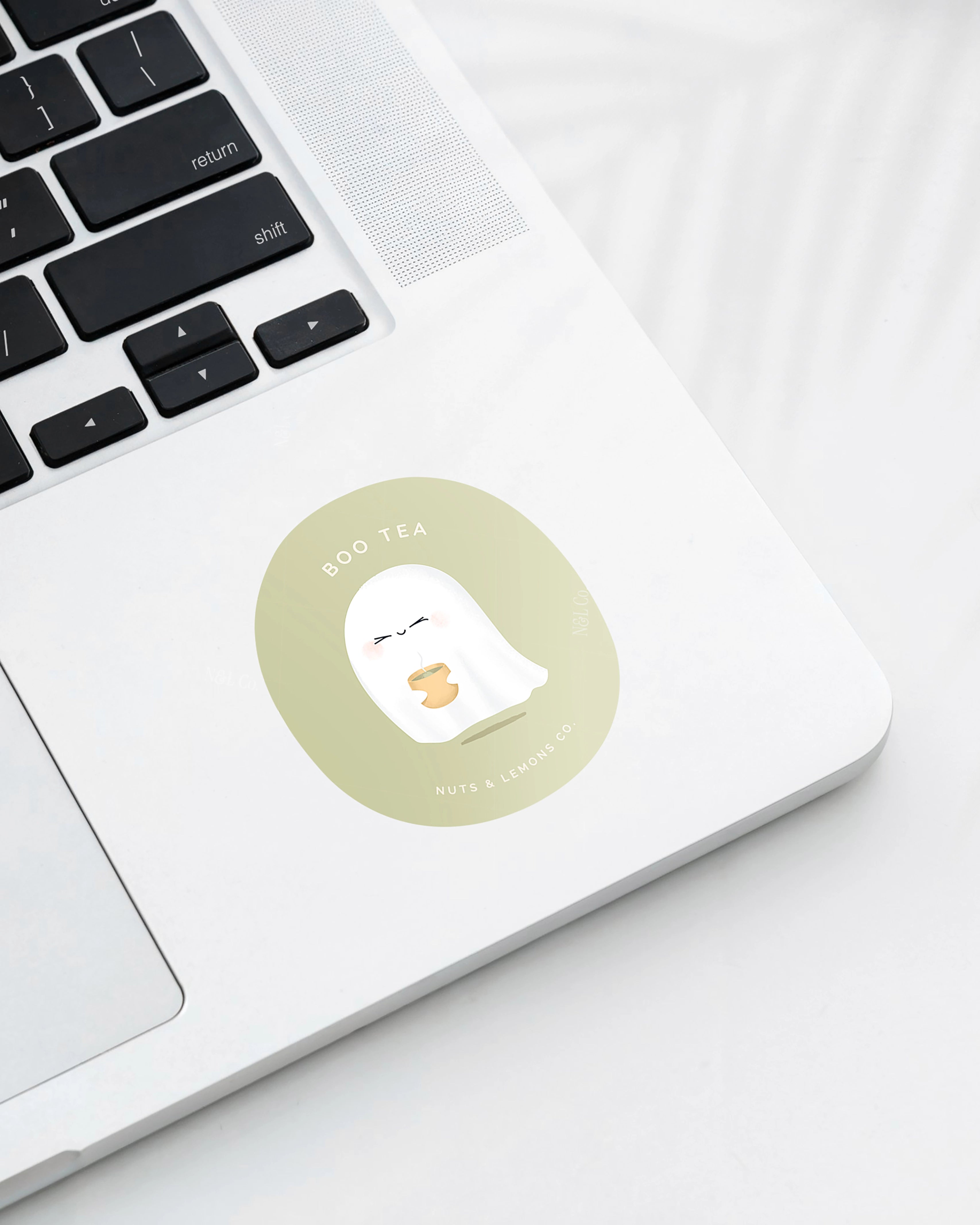Laptop displaying a Nuts & Lemons Co. diecut sticker featuring  a cute ghostie holding hot green tea with the phrase “boo tea”