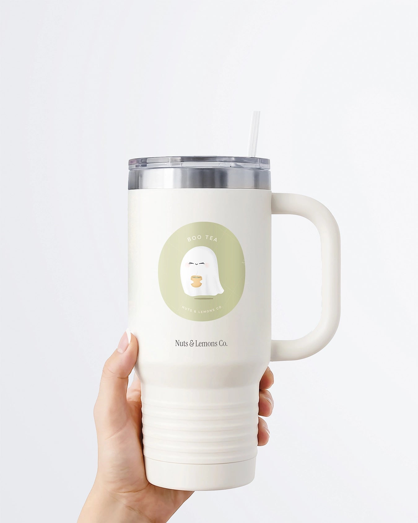 Hand holding a tumbler displaying Nuts & Lemons Co. diecut sticker featuring  a cute ghostie holding hot green tea with the phrase “boo tea”