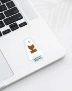 Laptop displaying a Nuts & Lemons Co. diecut sticker featuring a polar bear chomping a brick of chocolate with the phrase “mine”