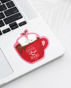 Laptop displaying a Nuts & Lemons Co. diecut sticker featuring a mug of hot cocoa with two marshmallows getting spicy with the phrase “I like my cocoa & books hot”