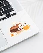 Laptop displaying a Nuts & Lemons Co. diecut sticker featuring  a stack of autumnal books, candle and psl with the phrase “cozy season and chapters”
