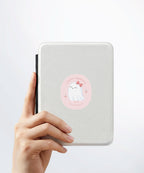 A hand holding a white kindle cover with a Nuts & Lemons Co. diecut sticker on it featuring a calm shiitake mushroom with the phrase “Let That Shittake Go”