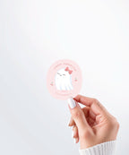 Hand holding a Nuts & Lemons Co. diecut sticker featuring a cute ghostie with a pink bow surrounded by heart cherries with the phrase “lookin’ faboolous”