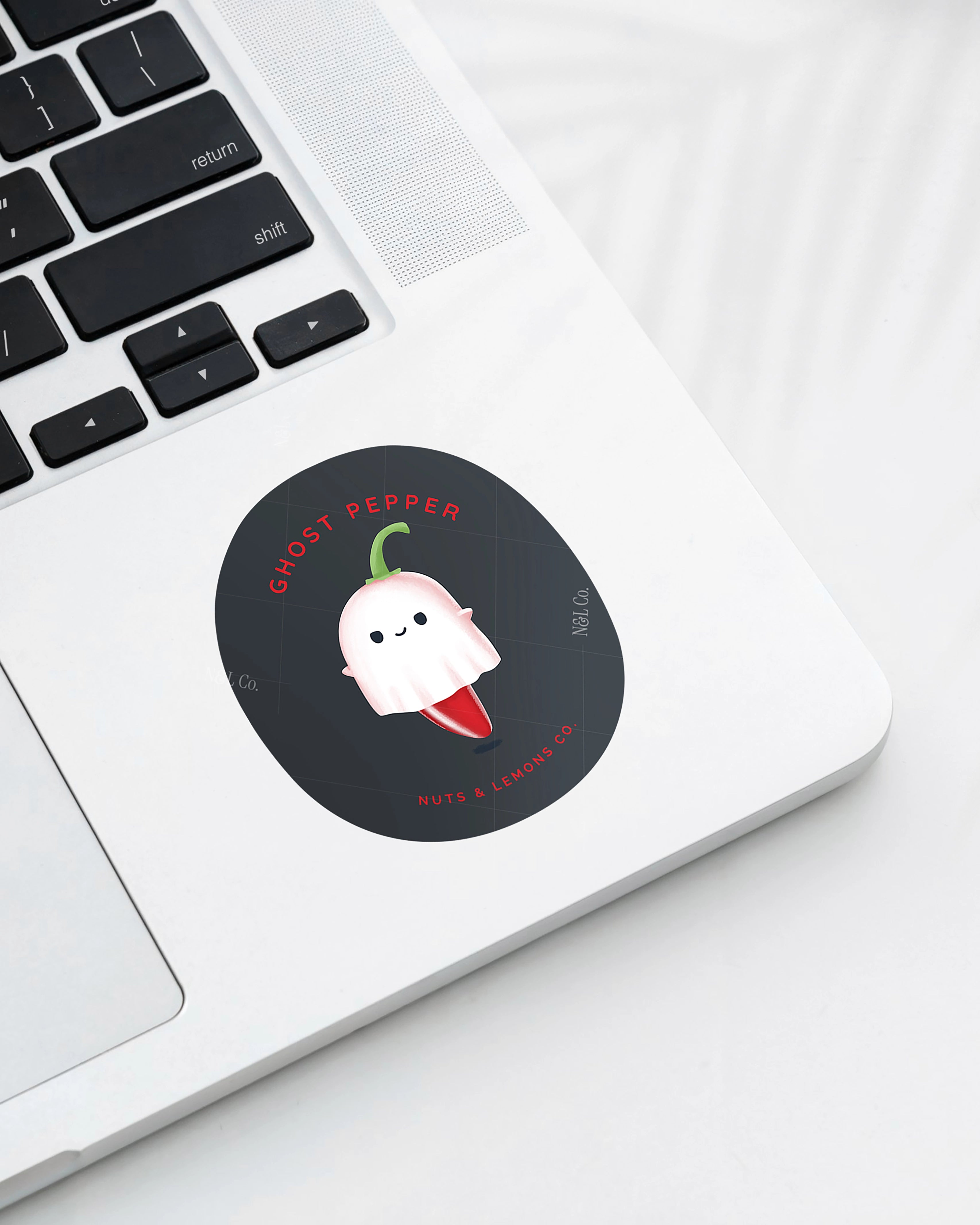 Laptop displaying a Nuts & Lemons Co. diecut sticker featuring a cute ghost pepper dressed as a ghostie  with the phrase “ghost pepper”
