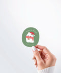 Hand holding a Nuts & Lemons Co. diecut sticker featuring a cute ghostie with books, Santa hat and scarf  with the phrase “ghoul’d reads”