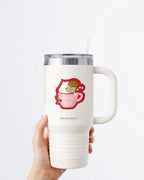 Hand holding a tumbler displaying Nuts & Lemons Co. diecut sticker featuring a blushing gingerbread reading a spicy book while holding a candy cane hot tubbing in a pink mug with the phrase 