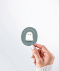 Hand holding a Nuts & Lemons Co. diecut sticker featuring a cute annoyed ghostie with the phrase “keep the boo sheet”