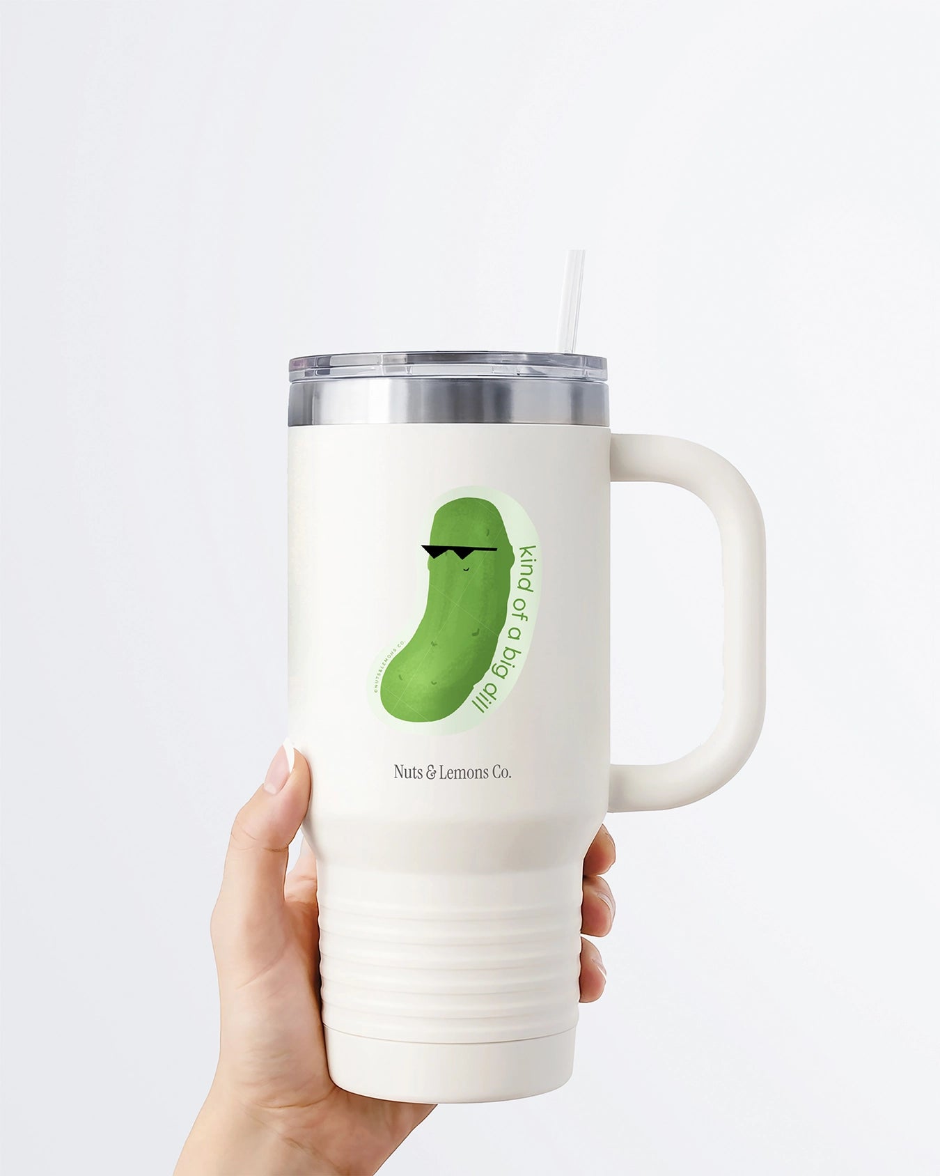 Hand holding a tumbler displaying Nuts & Lemons Co. diecut sticker featuring a dill pickle with shades with the phrase “kind of a big dill”