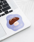 Laptop displaying a Nuts & Lemons Co. diecut sticker featuring a calm shiitake mushroom with the phrase “let that shiitake 
