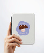 A hand holding a white kindle cover with a Nuts & Lemons Co. diecut sticker on it featuring a calm shiitake mushroom with the phrase “Let That Shittake Go”