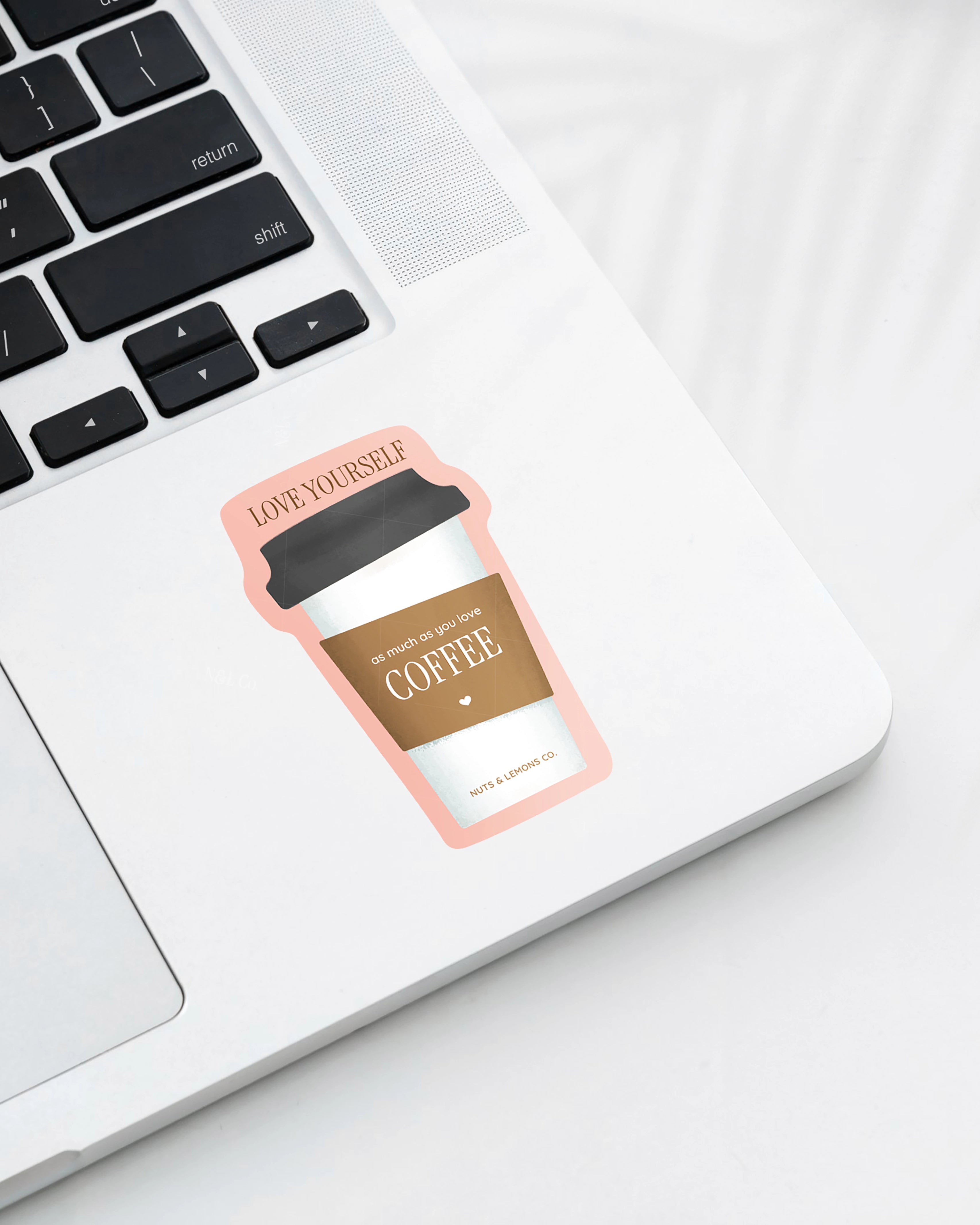 Laptop displaying a  Nuts & Lemons Co. diecut sticker featuring a togo coffee with the phrase “love yourself like you love your coffee”