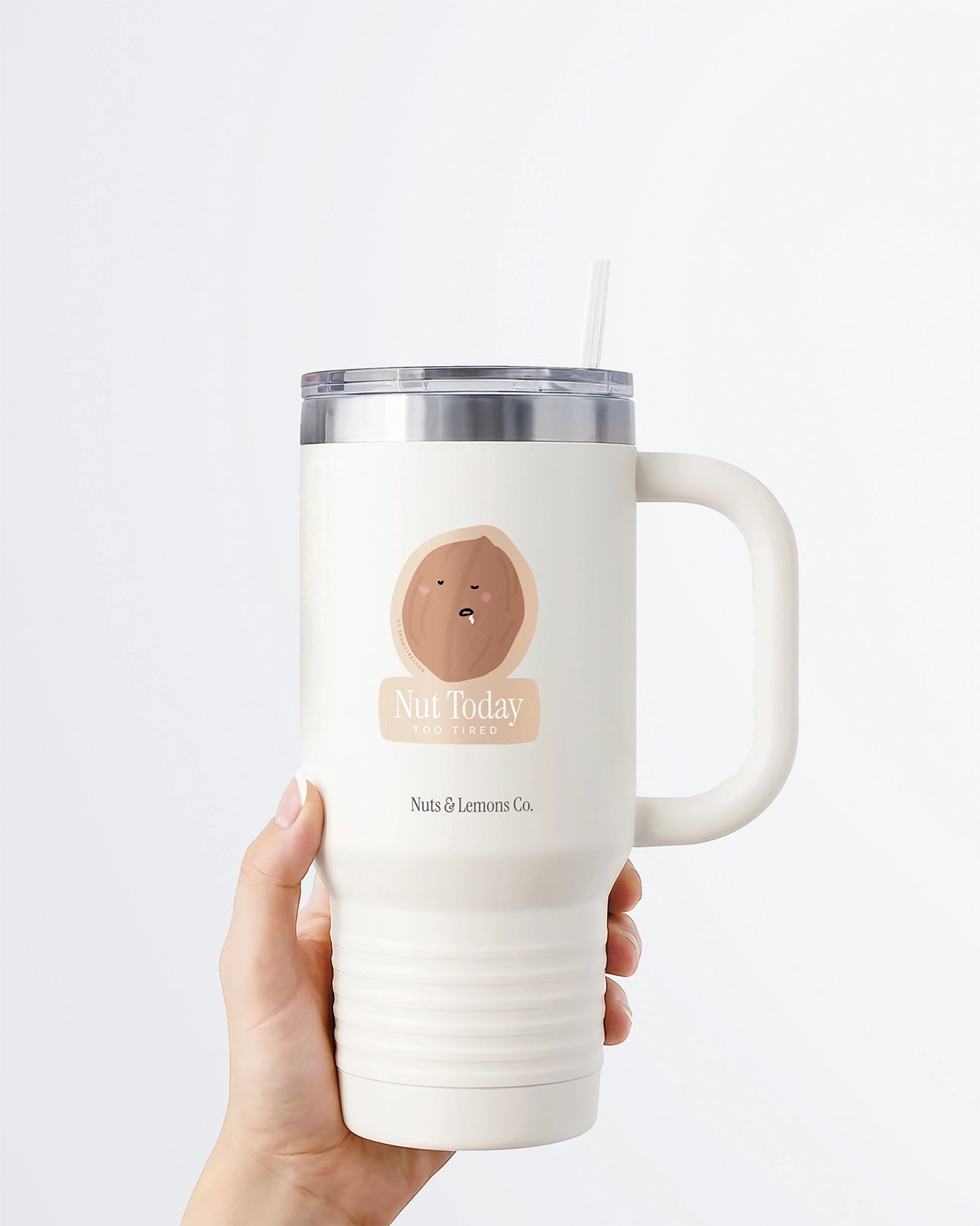 Hand holding a tumbler displaying Nuts & Lemons Co. diecut sticker featuring a walnut drooling asleep with the phrase “nut today too tired”