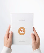 A pair of hands holding a white notebook with a Nuts & Lemons Co. diecut sticker on it featuring a cute ghostie with autumn books, scarf and pumpkin spice latte with the phrase “Pumpkin Spice Ghoulie”