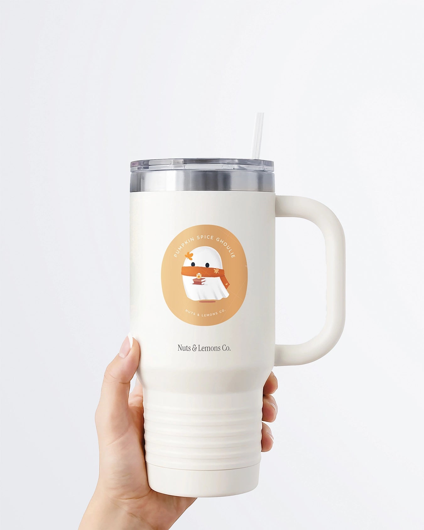 Hand holding a tumbler displaying Nuts & Lemons Co. diecut sticker featuring a cute ghostie with autumn books, scarf and psl with the phrase “pumpkin spice ghoulie”