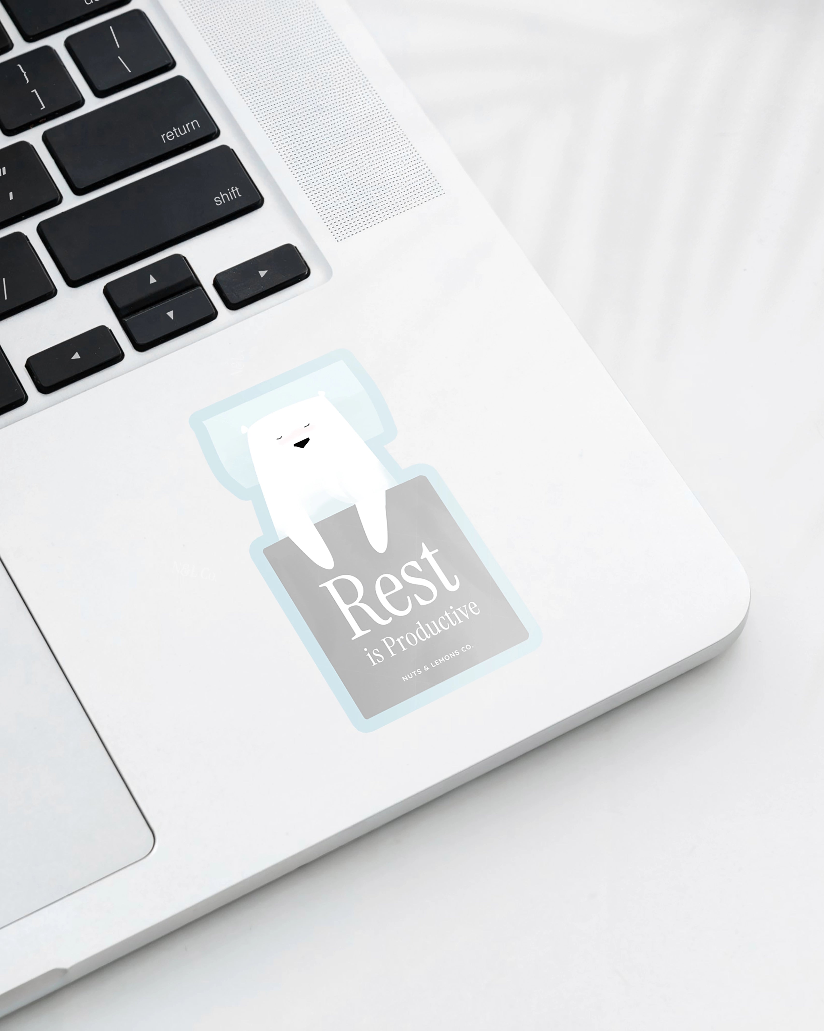 Laptop displaying a Nuts & Lemons Co. diecut sticker featuring sleeping polar bear with the phrase “rest is productive”