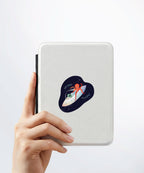 A hand holding a white kindle cover with a Nuts & Lemons Co. diecut sticker on it featuring an ufo with an alien and octopus with the phrase “Two Peas on a Pod”