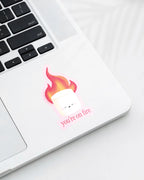 Laptop displaying a Nuts & Lemons Co. diecut sticker featuring a marshmallow on fire with the phrase “you’re on fire”